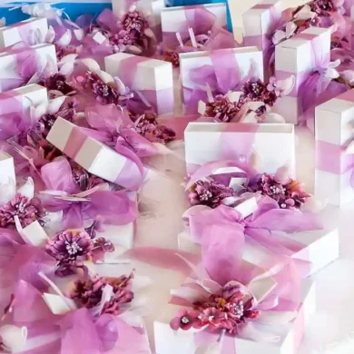 wedding favors packed in small boxes with purple ribbon and flower