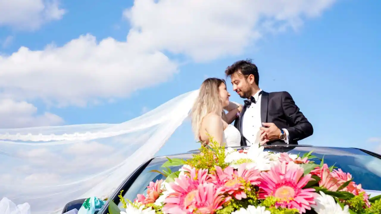 groom and bride in car decorated with real flowers