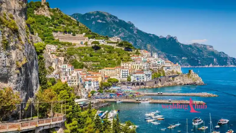 A Malaysian couple exchanging vows on a flower-adorned terrace overlooking the vibrant town of Positano and the blue sea on the Amalfi Coast.