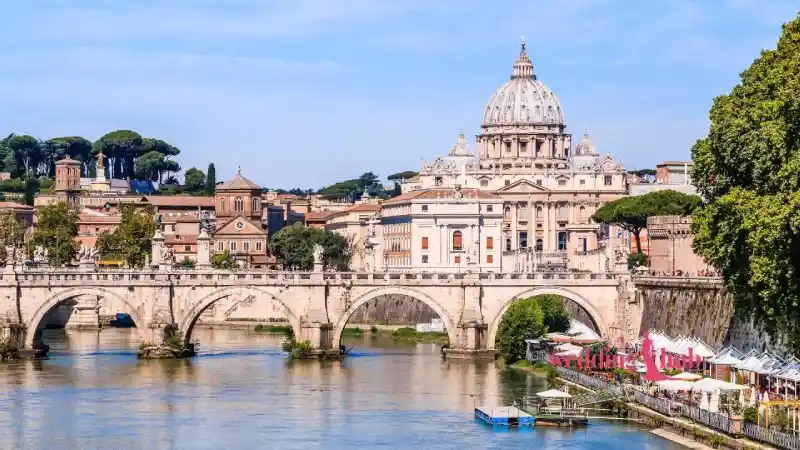 A Malaysian couple sharing a moment on a Rome rooftop at dusk, with the illuminated Colosseum visible in the background.